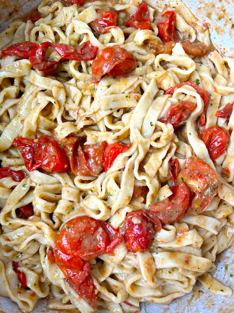 cooked pasta in a pot with roasted cherry tomatoes