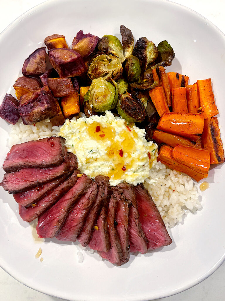 rice bowl with roasted, vegetables, whipped feta, steak and hot honey