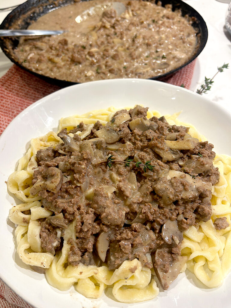 sourdough pasta with venison stroganoff on top in a white bowl