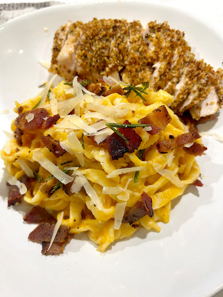 white bowl of pumpkin carbonara pasta with breaded chicken