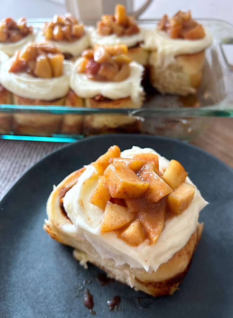 cinnamon bun on a plate with cream cheese icing and apple pie filling