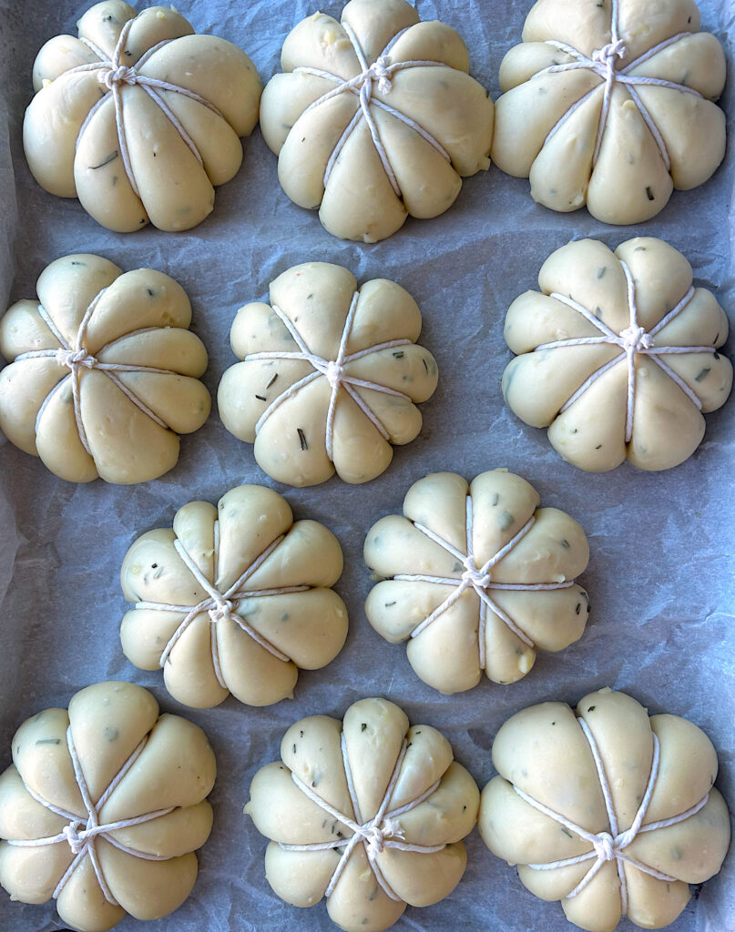 unbaked buns on a baking sheet tied with butchers string