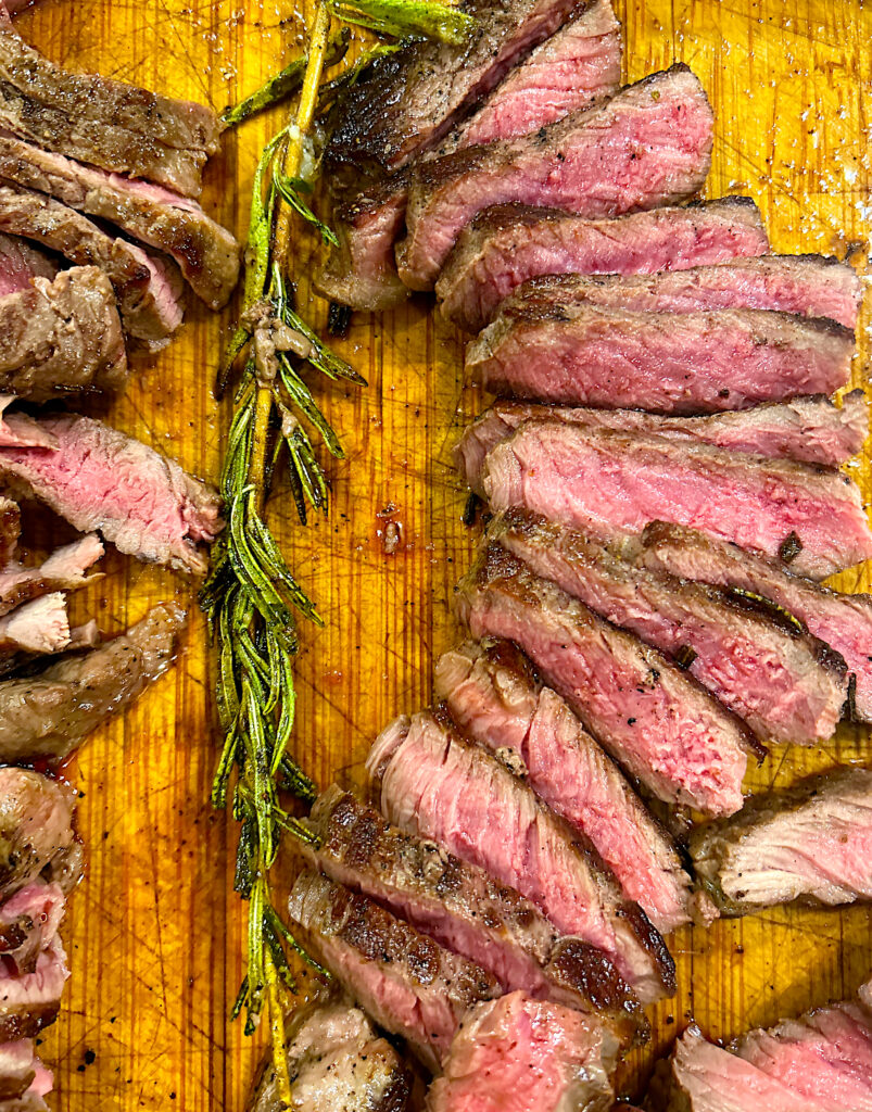 sliced medium rare steak on a wood board 