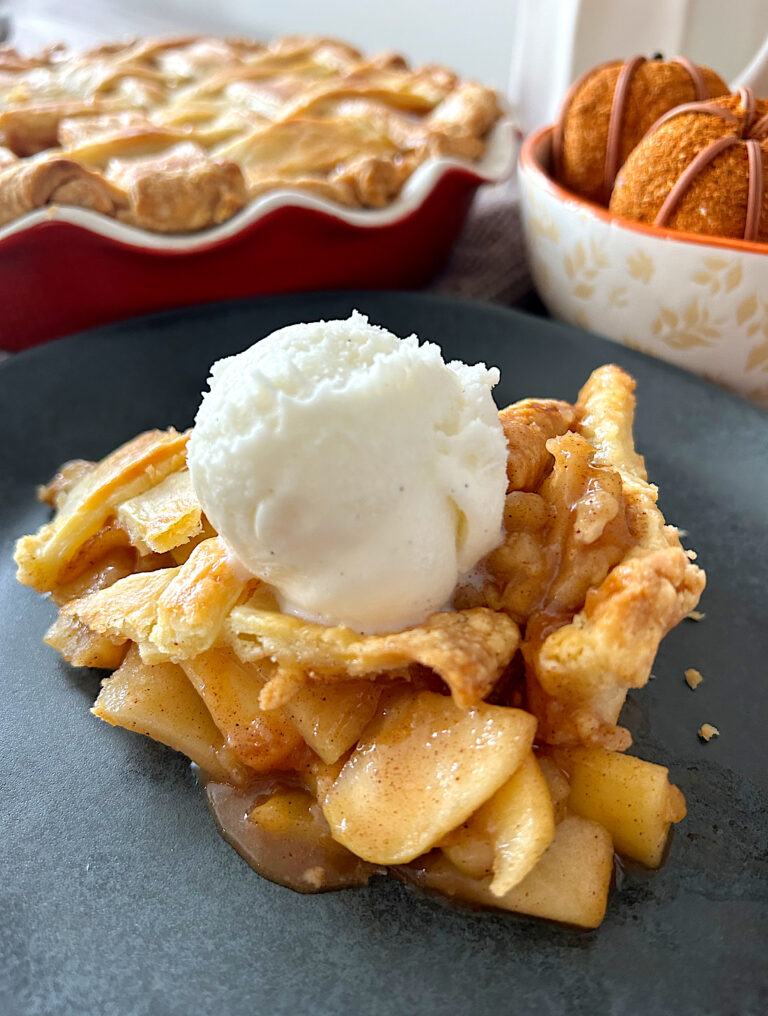 slice of apple pie with vanilla cream on a black plate