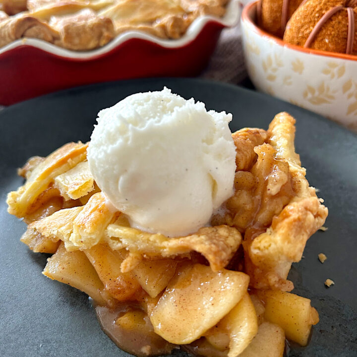 slice of apple pie with vanilla cream on a black plate
