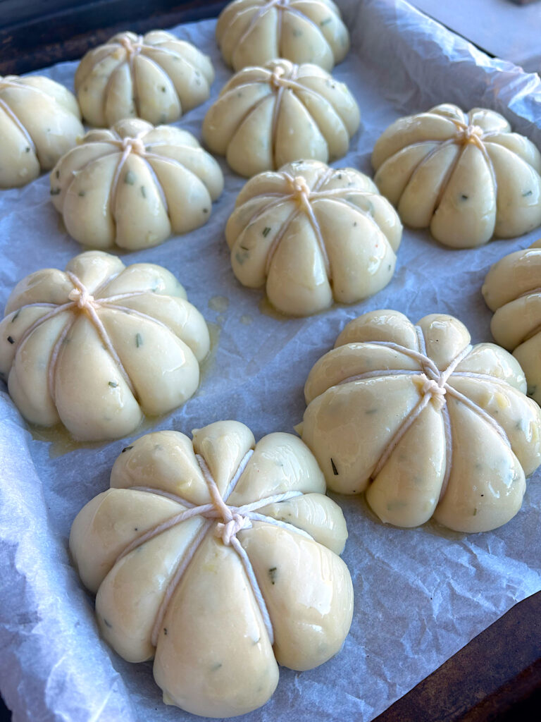 a tray of risen unbaked garlic pumpkin buns