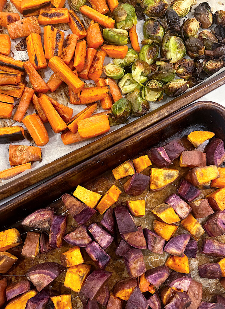 roasted sweet potatoes, carrots and Brussel sprouts on a baking sheet