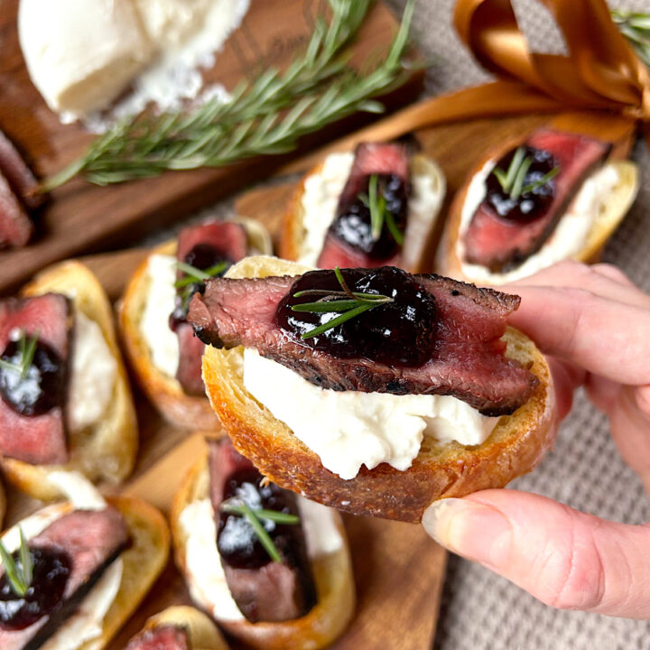 a crostini with burrata cheese, venison steak and blackberry jam