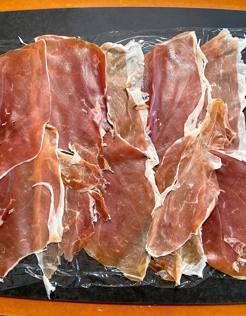 prosciutto laid out on a black board