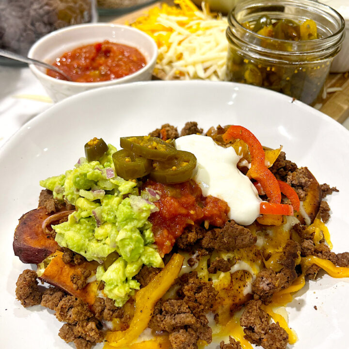 a white bowl with sweet potatoes, peppers, onions, ground venison and nacho toppings