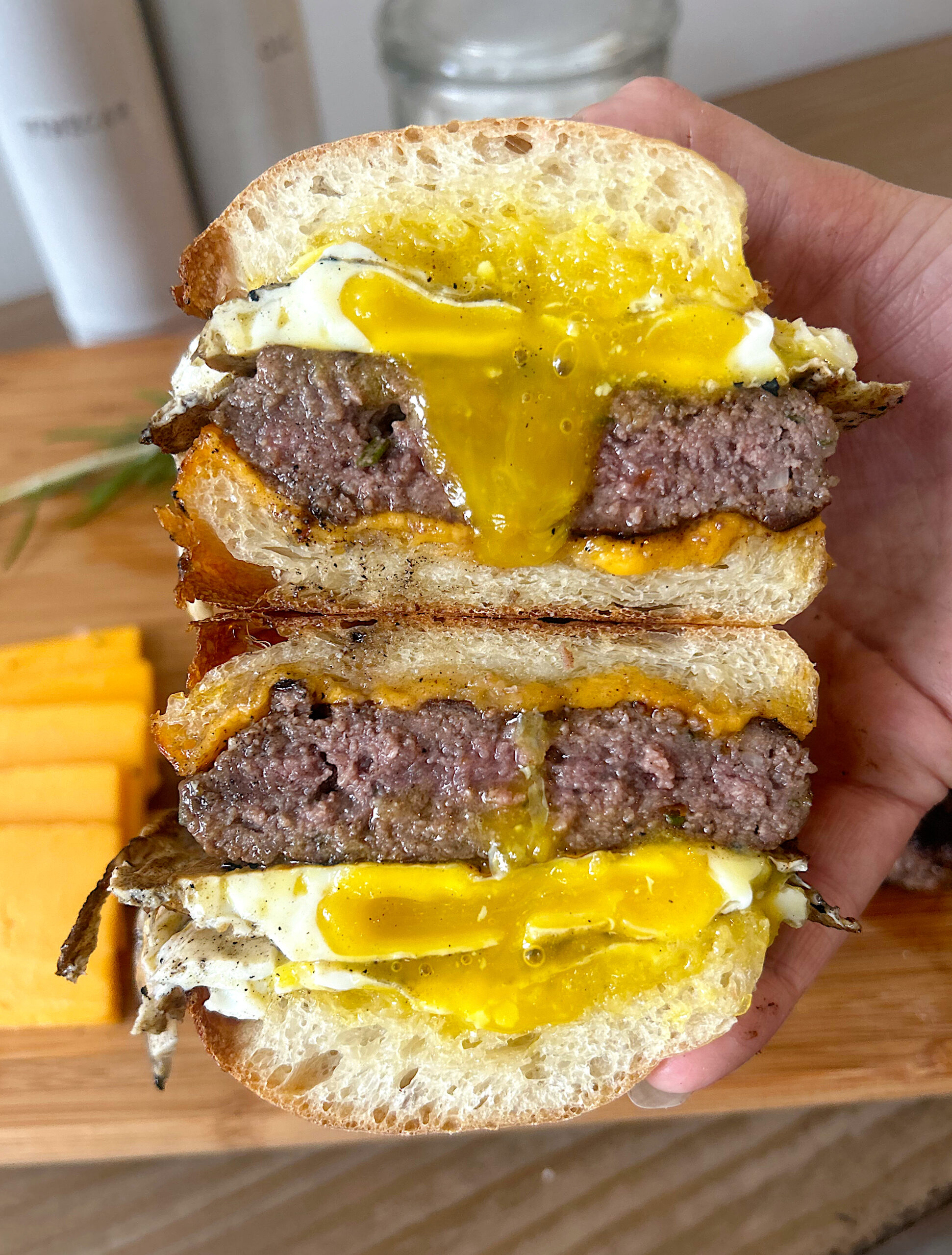 a breakfast sandwich cut in half with egg, cheese and venison sausage