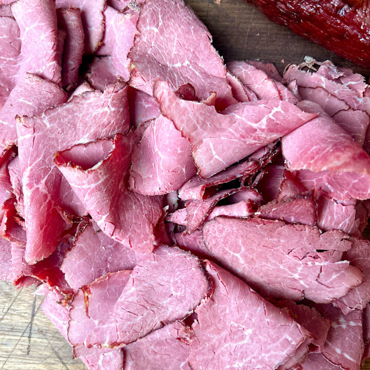 homemade venison pastrami thinly sliced on a wood board