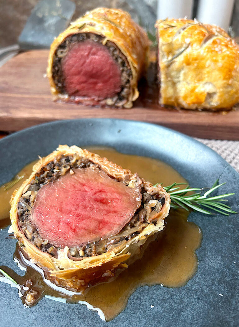 venison wellington cut in half , with a slice on a blue plate