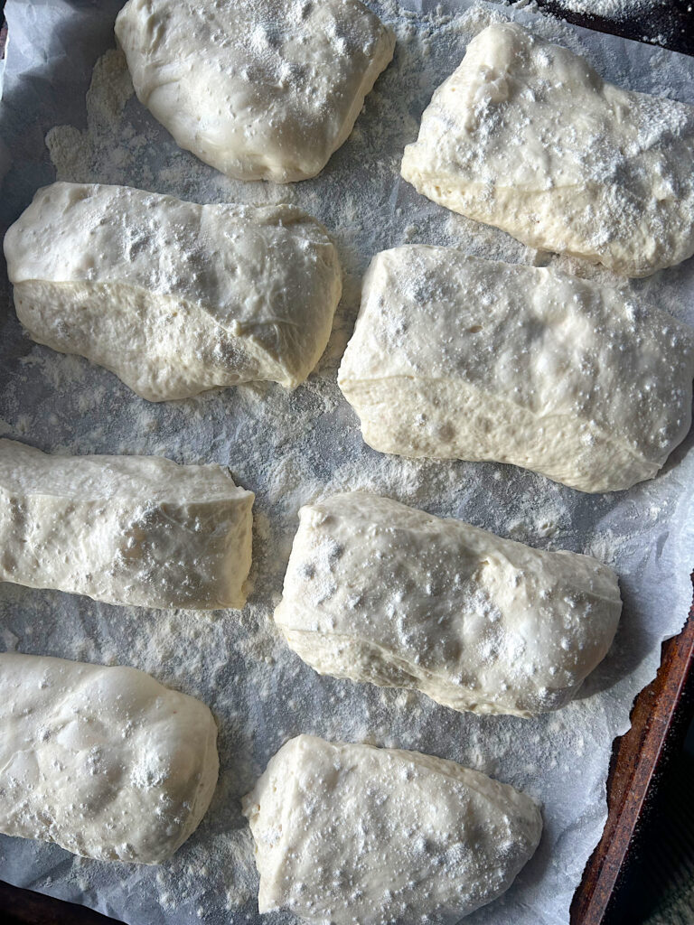 unbaked rectangular sourdough buns on a baking sheet