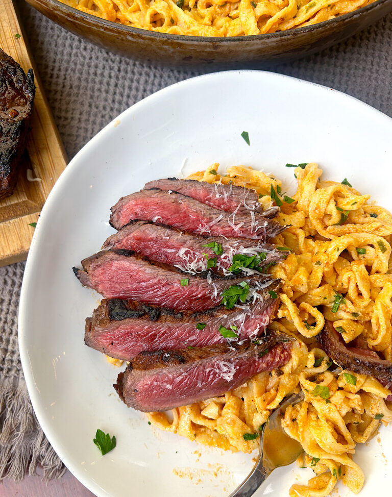 a white bowl full of linguini pasta with steak on top