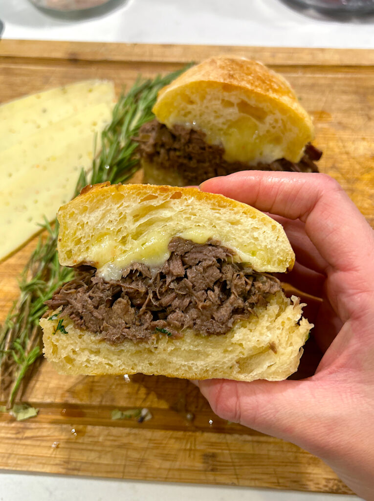 French dip sandwich with venison on a wood board