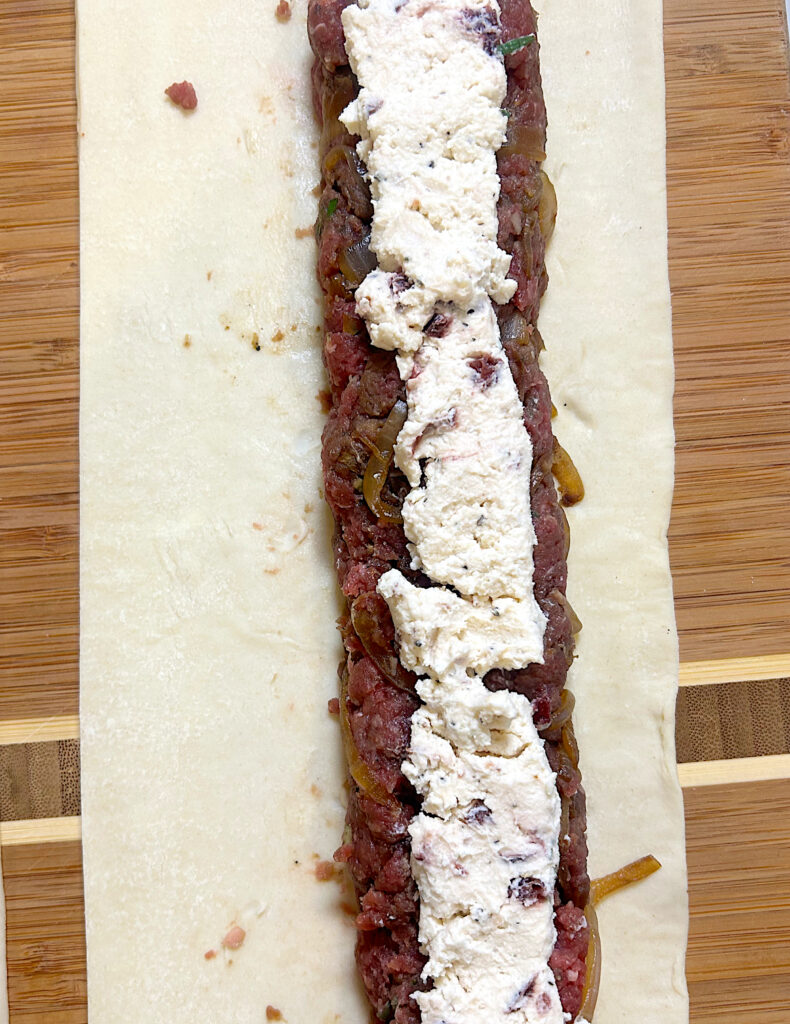 a sheet of puff pastry with ground meat filling and boursin cheese