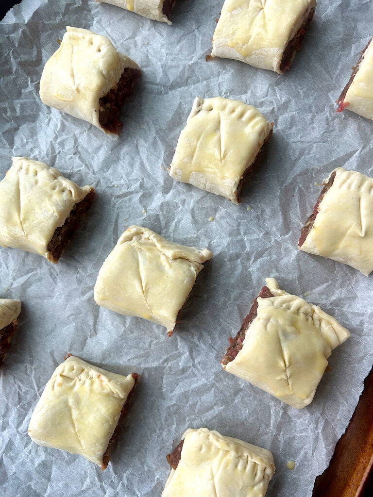 a baking sheet with unbaked mini sausage rolls