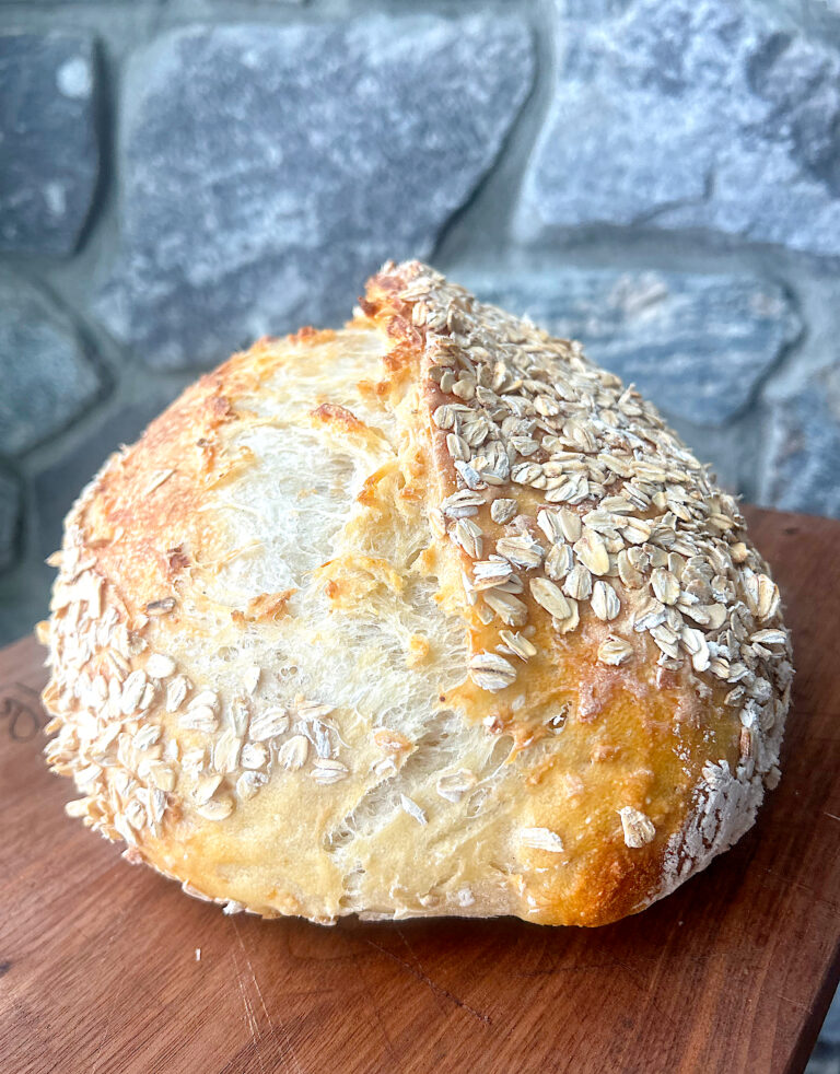 a loaf of oat sourdough bread on a wood board