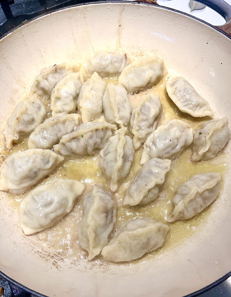 gyozas being steamed in a skillet