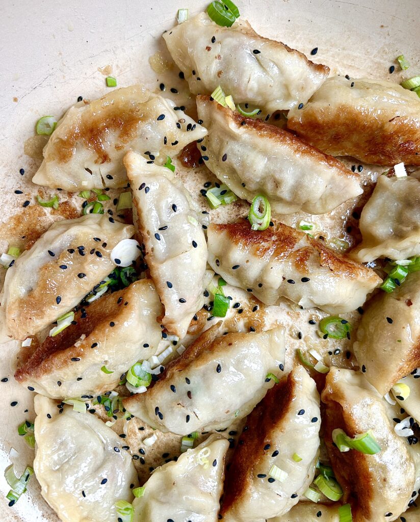 a pan full of golden crispy gross with green onions and sesame seeds