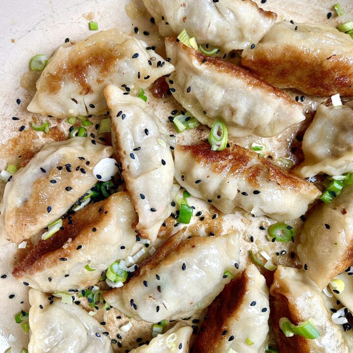 a pan full of golden crispy gross with green onions and sesame seeds