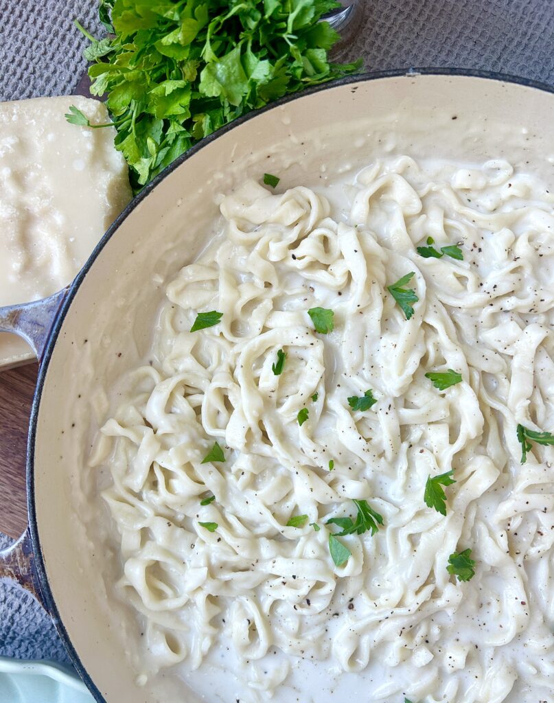 a large skillet full of fettuccine pasta with a white cream sauce