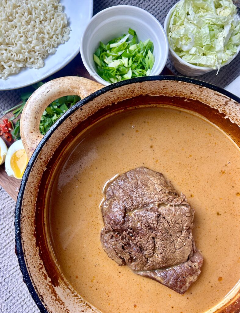 a pot with broth and a venison roast