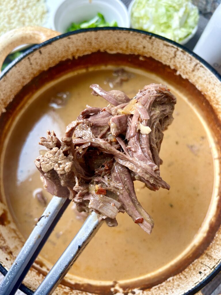 a pot of broth and shredded venison roast meat