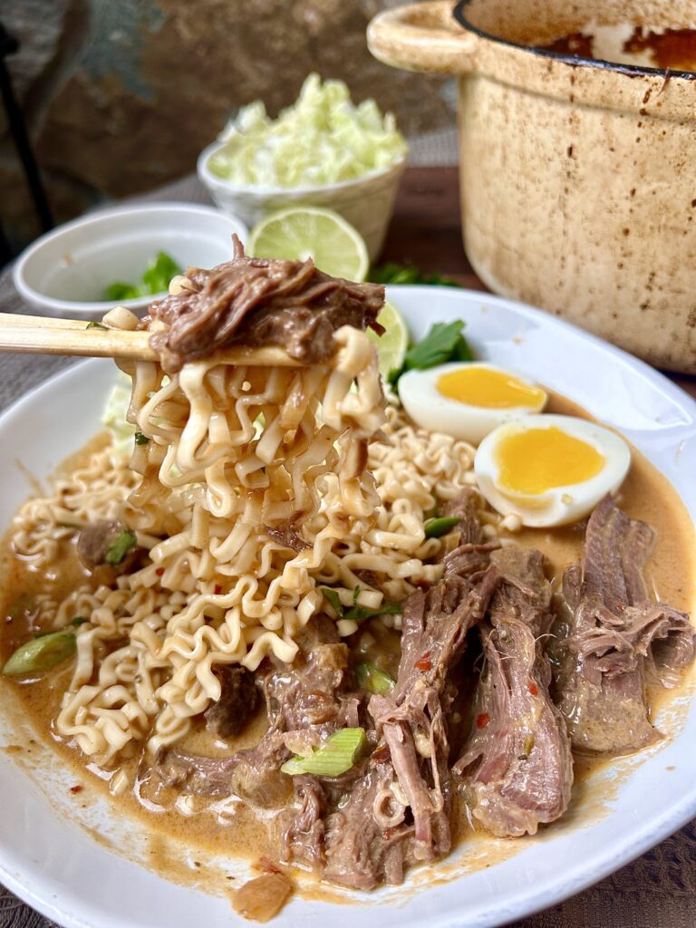 a white bowl of curry ramen noodles with shredded meat