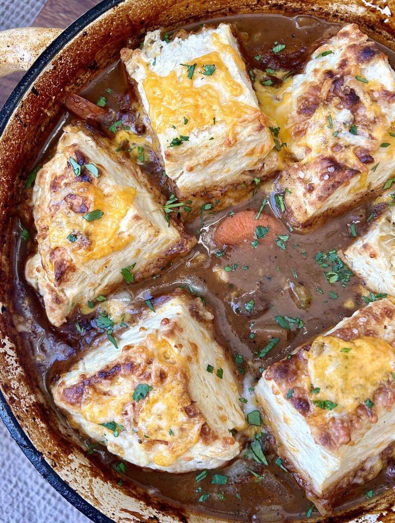 a pot of meat stew with cheese biscuits on top