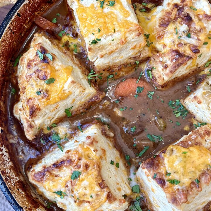 a pot of meat stew with cheese biscuits on top