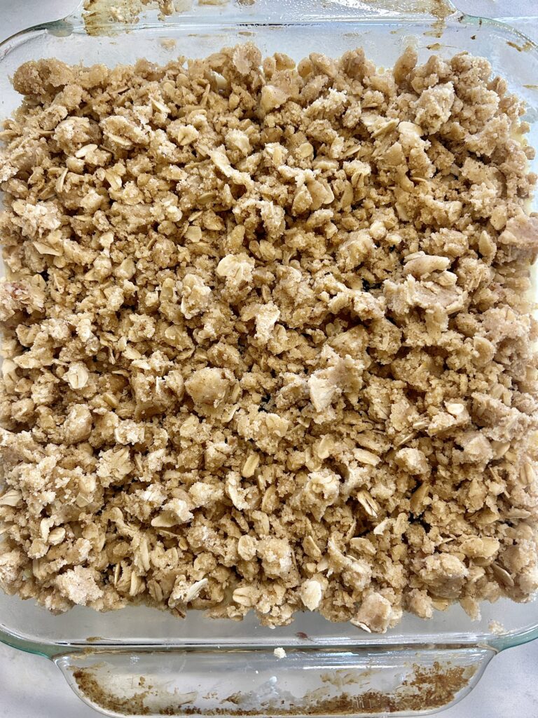 an unbaked cake with a crumble topping in a glass baking dish