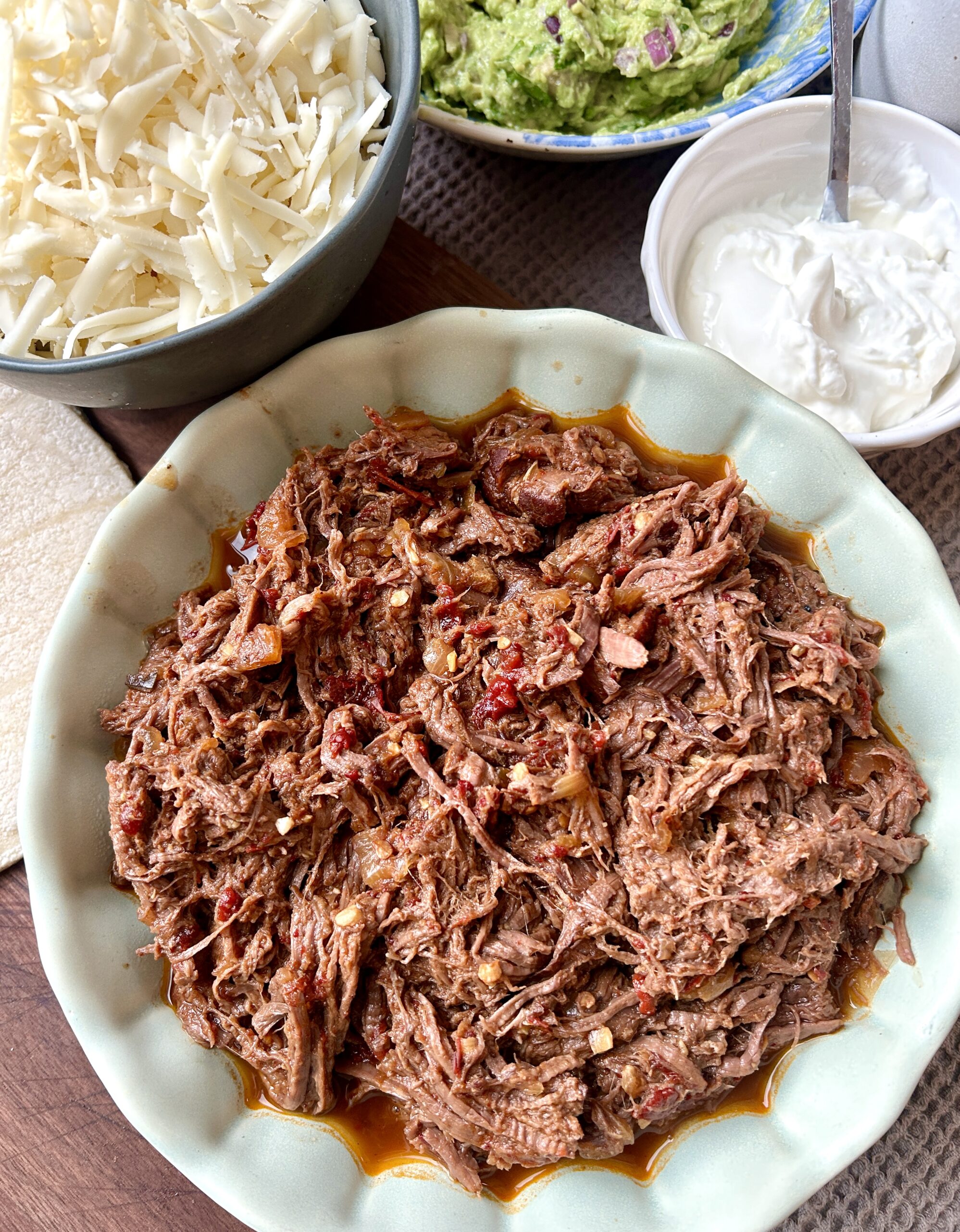 a green bowl full of shredded venison meat