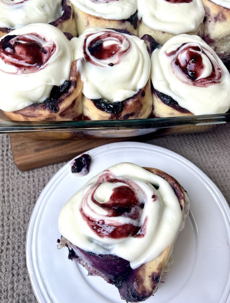 a white plate with a blueberry cinnamon bun on it