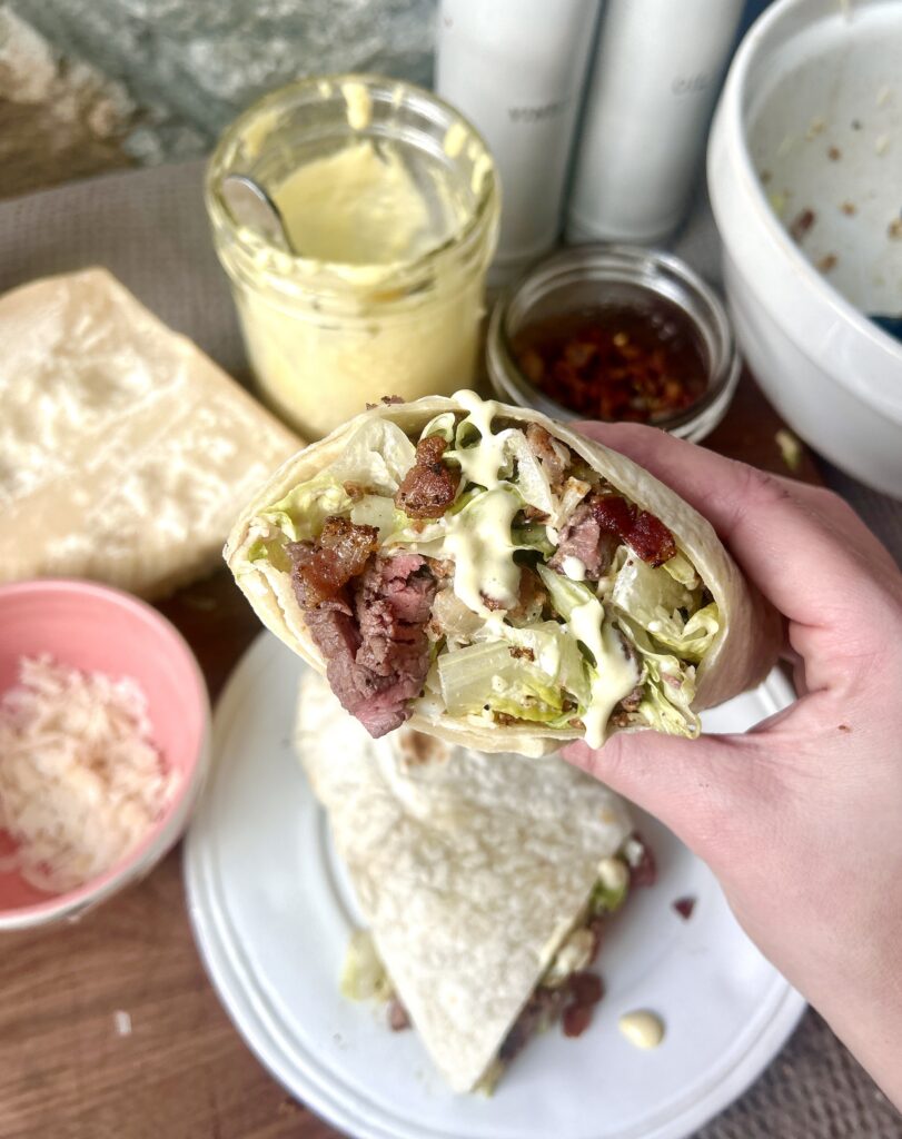 half of a steak caesar salad wrap with bacon in it