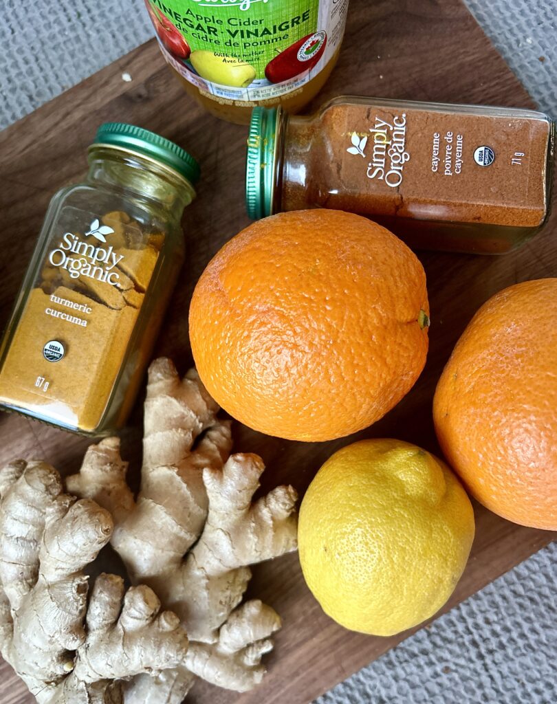 oranges, lemon ginger, cayenne and turmeric on a wood board
