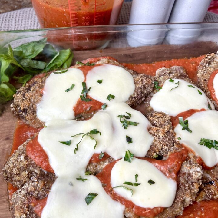 a baking dish with crispy venison cutlets, tomato sauce and mozzarella