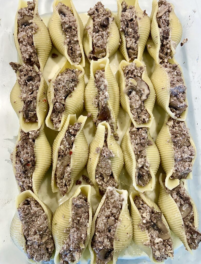 a baking dish of shell pasta stuffed with a meat and mushroom filling