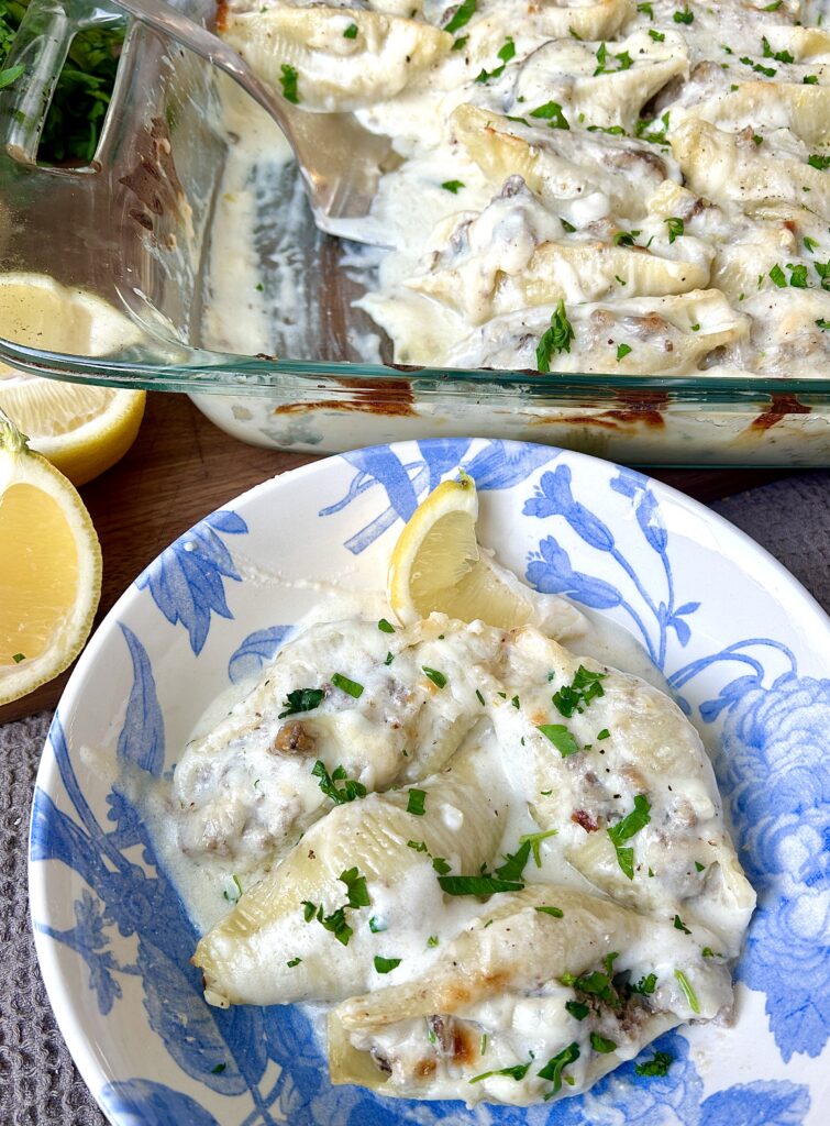 a white and blue bowl of with meat stuffed pasta and creamy sauce