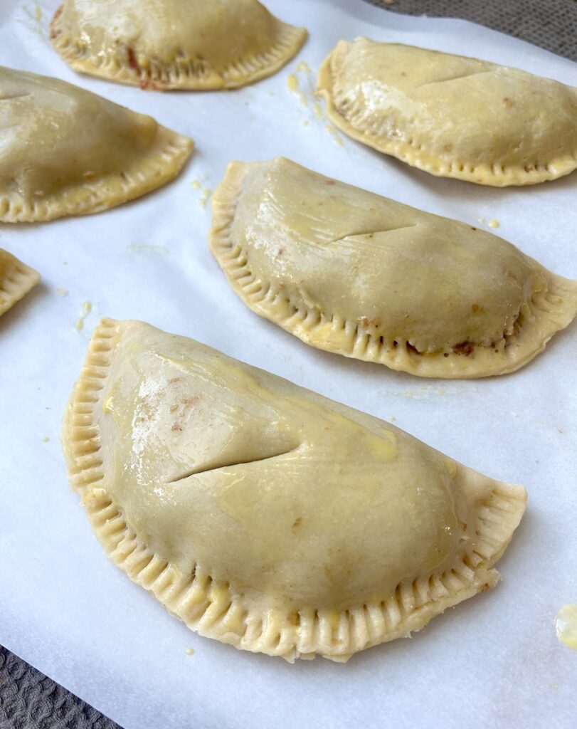unbaked savoury hand pies on a baking sheet