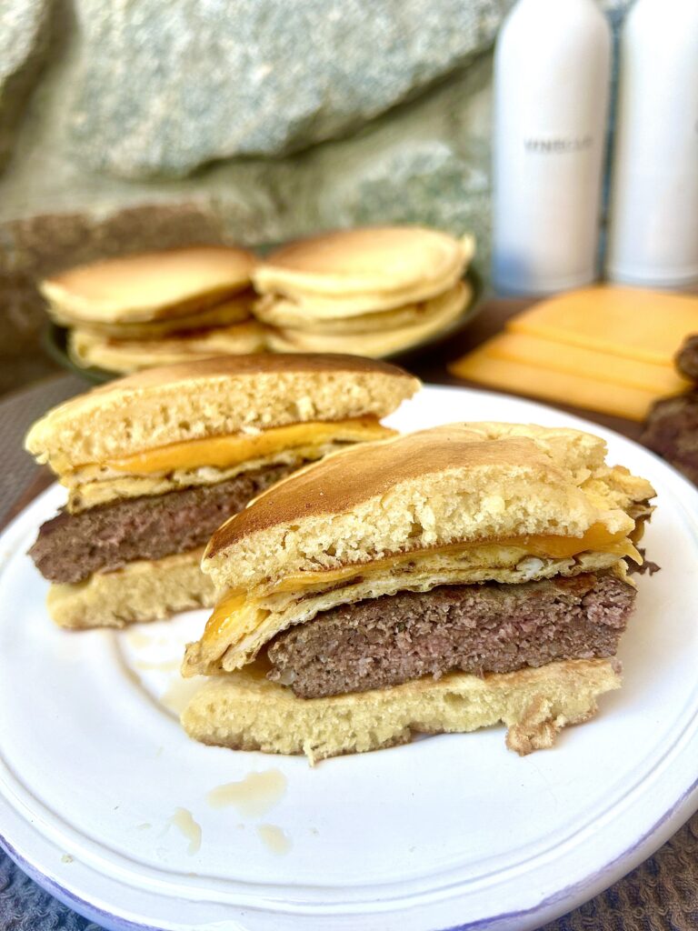 a white plate with an egg, sausage and cheese breakfast sandwich