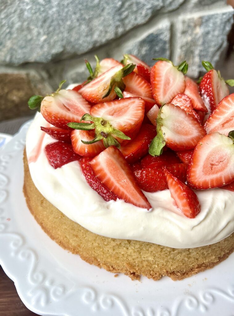 a vanilla cake topped with whipped cream and strawberries