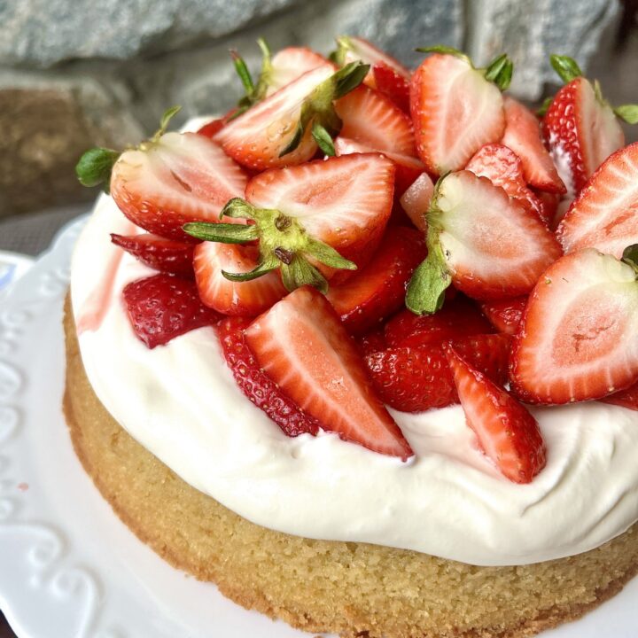 a vanilla cake topped with whipped cream and strawberries