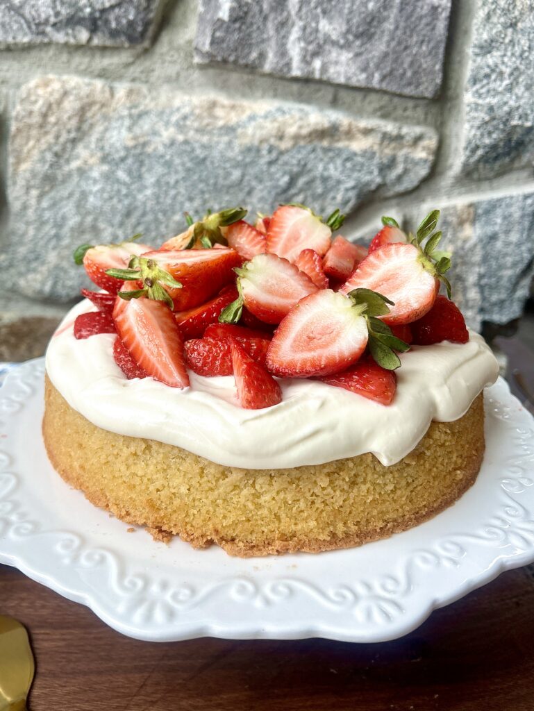 a strawberry shortcake with whipped cream on a white cake plate