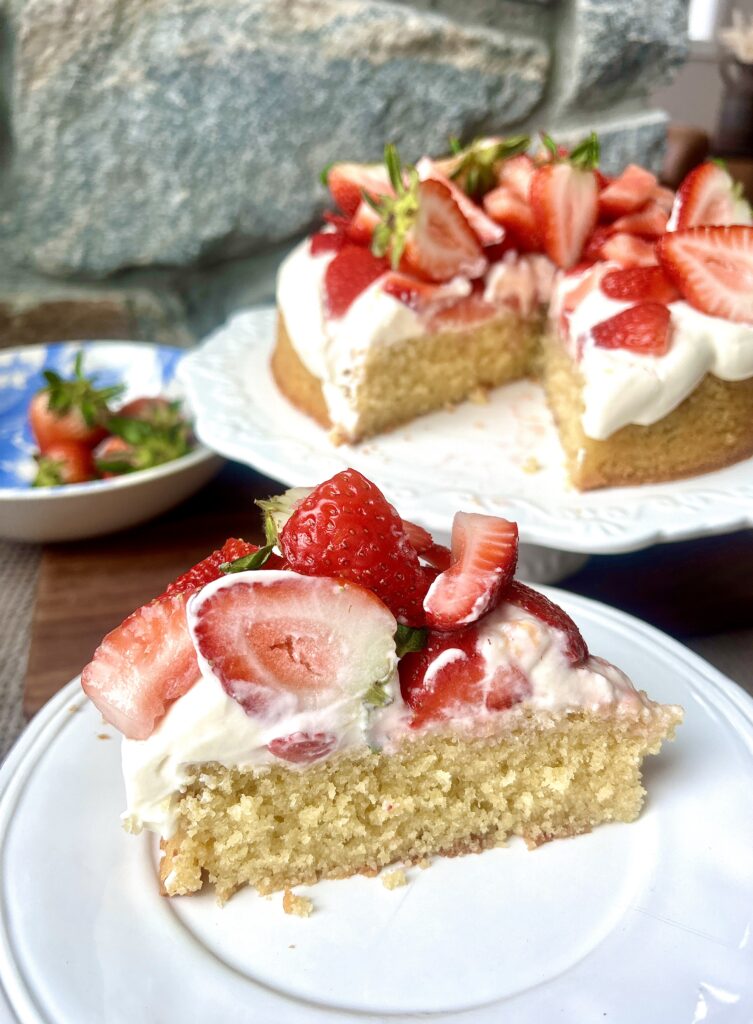 a sliced of cake on a white plate with strawberries on top