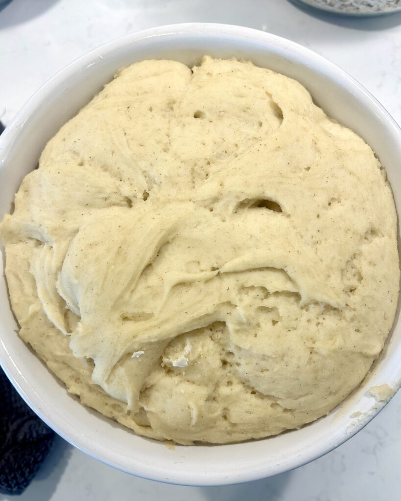 a white bowl of proofed dough