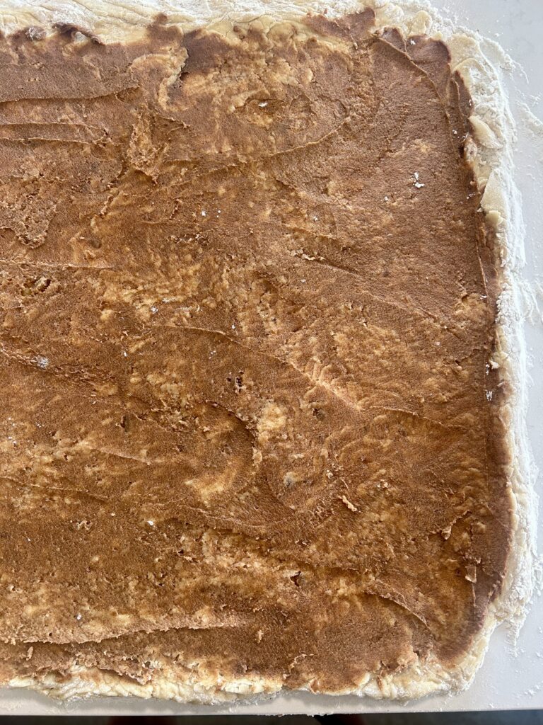 dough rolled out into a rectangle with cinnamon and brown sugar filling on top