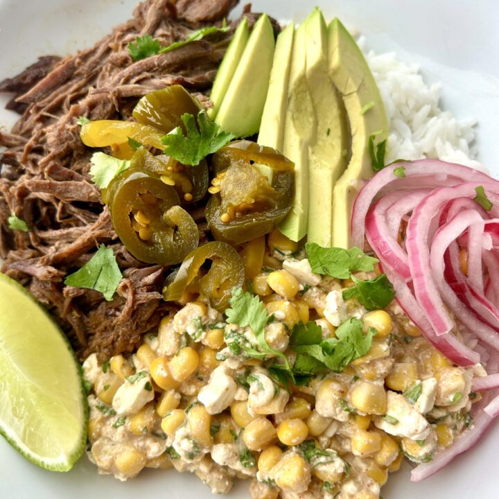 a rice bowl with street corn, shredded meat, avocado and onion