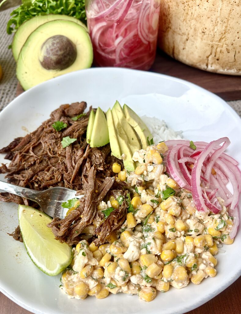 a rice bow with shredded venison, corn, avocado and red onions